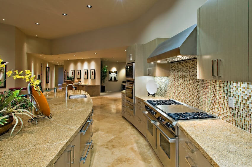 微微弯曲的厨房配有大胆的玻璃马赛克瓷砖后挡板和浅色花岗岩台面。