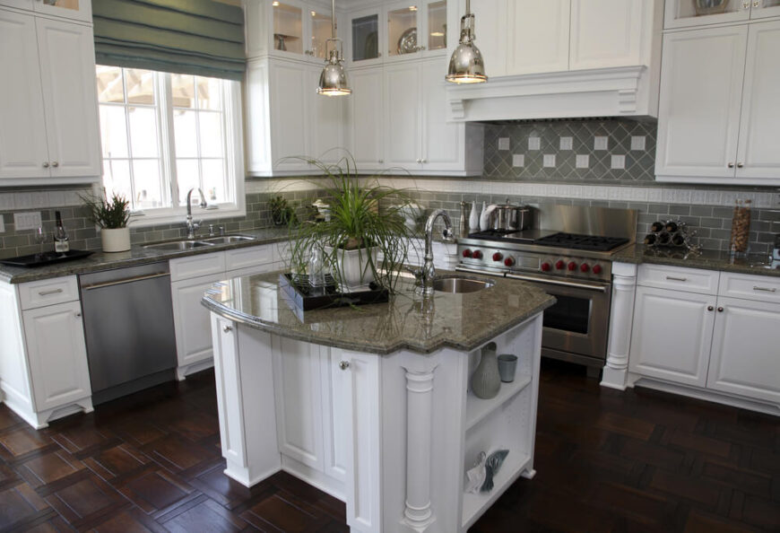 一间现代化的厨房，中间有一个小岛台和漂亮的木地板。灰色的地铁瓷砖让位于华丽的瓷砖，然后是焦点马赛克。
