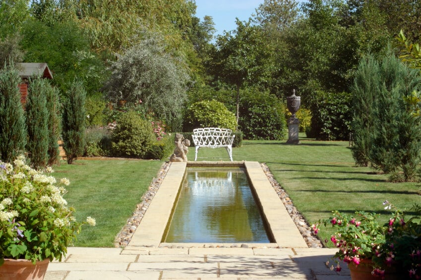 一个更国际化的游泳池从天井延伸到院子里，以白色长凳和角度雕像结束。院子两边排列着常青树和其他大树和灌木。