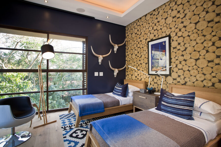 这间次级卧室的特点是大胆的风格突破，墙壁上有蓝色调和圆形木雕，以及以木框架床和未涂漆的地板为中心的质朴外观。