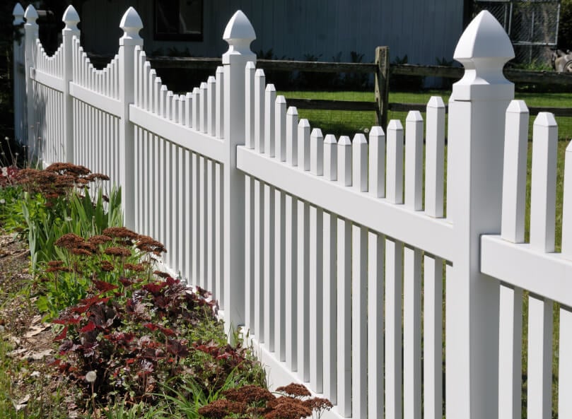 白色PVC尖桩栅栏与简单的景观和更乡村的栅栏背景。