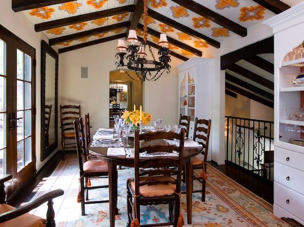 正式的餐厅在可俯瞰客厅的锻铁小阳台两侧设有大瓷柜。这个空间非常现代，但暴露的木梁之间天花板上的黄色模板增添了独特的魅力。