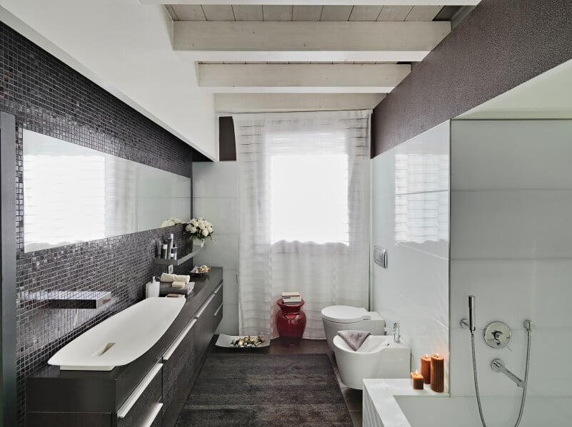 现代主浴室设有时尚的大型容器水槽，设置在黑色柜台上，与覆盖硬木地板的地毯相匹配。