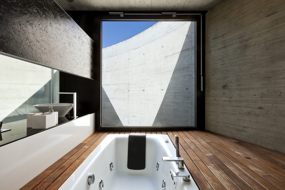 一个独特的主浴室设置，在硬木地板上设有一个插入式浴缸。房间里还有一对水槽。