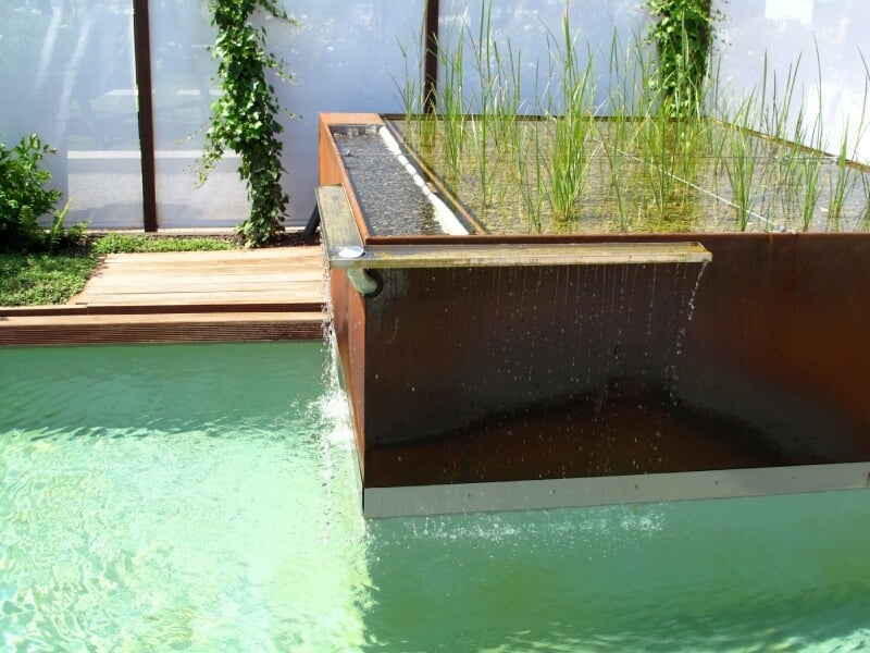 这是一个现代的瀑布，一个铜盒子，上面有一小群喜欢水的植物和一个小排水沟作为瀑布。