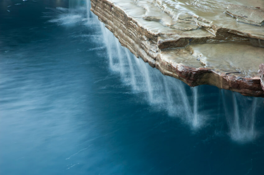 浇水倒入板岩瀑布的边缘到游泳池。