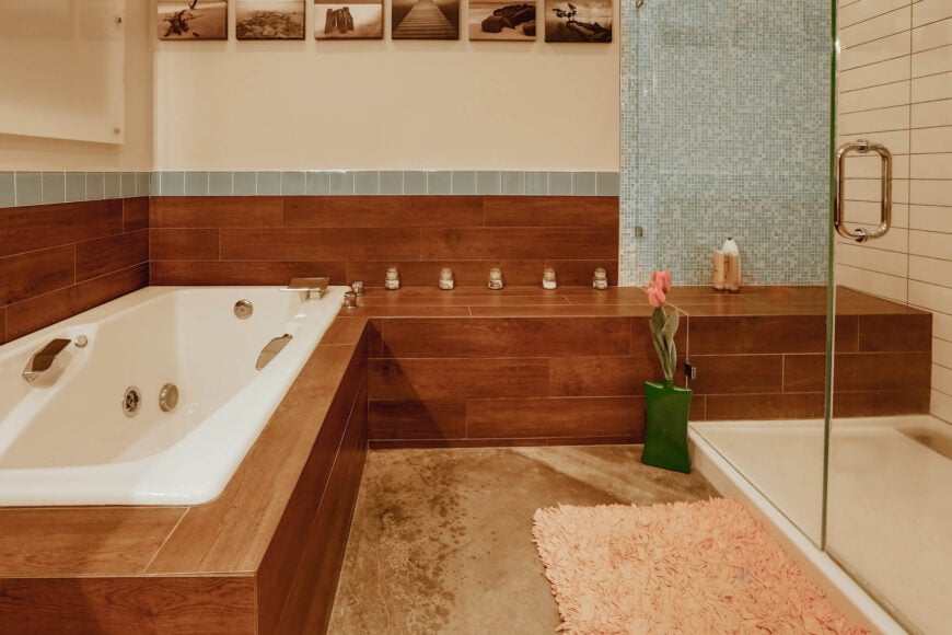 近距离观察，浴室周围有一大片丰富的木镶板，通往步入式淋浴间。蓝色瓷砖的微妙添加增加了各种细节。