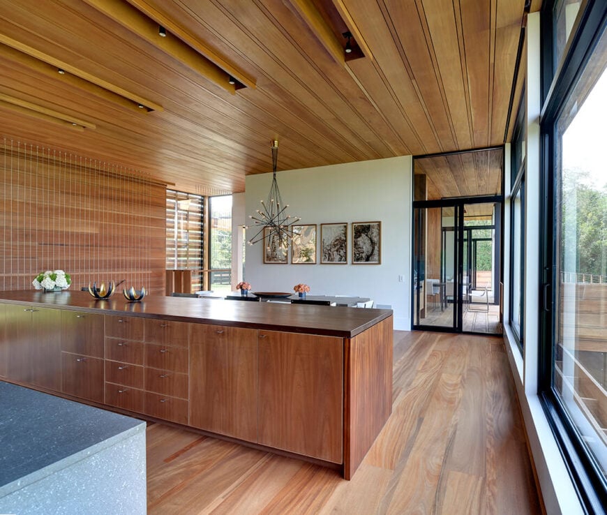 丰富的硬木地板与长岛和天花板上的极简主义镶板相辅相成，在整个住宅中均匀地运行。全高玻璃面板在视觉上打开了空间，共享户外空间。