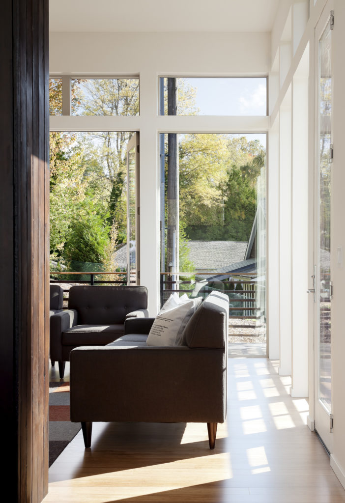 这个舒适的空间包括现代的深棕色沙发和椅子，与外部和烟囱的焦木外观相匹配。通过通高玻璃可以看到环绕式阳台。
