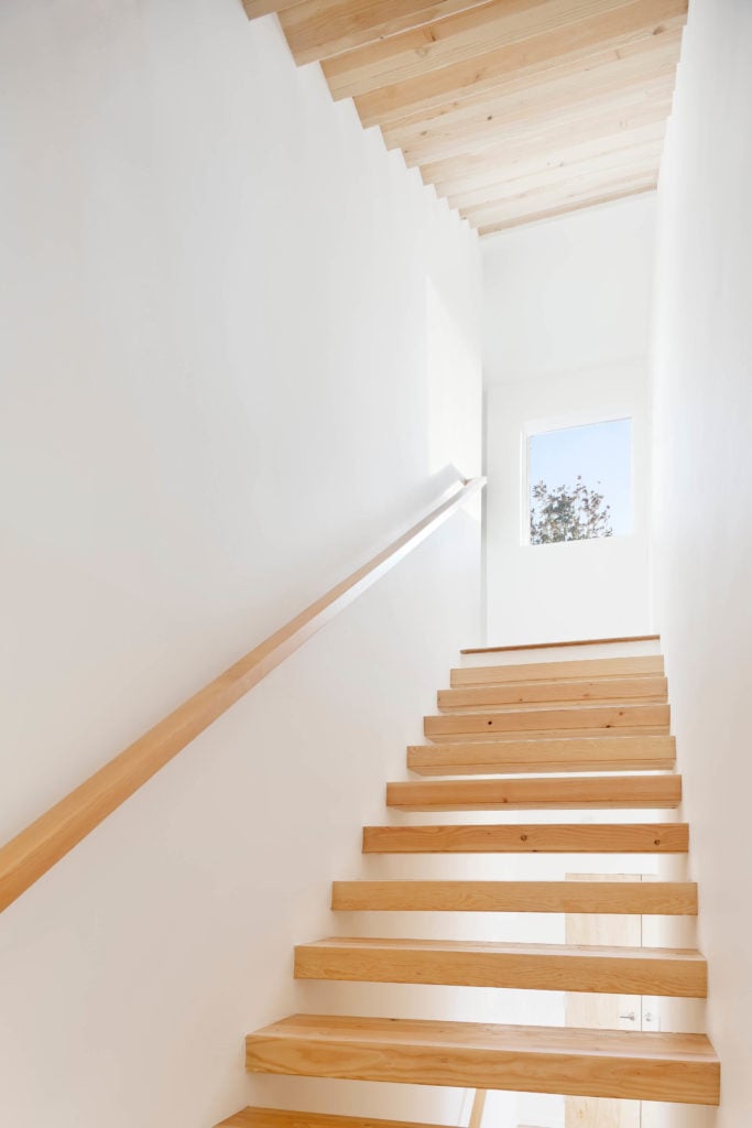 漂浮的楼梯设计与这些浅色的天然木板形成了完美的对比，与白色的环境形成了鲜明的对比。