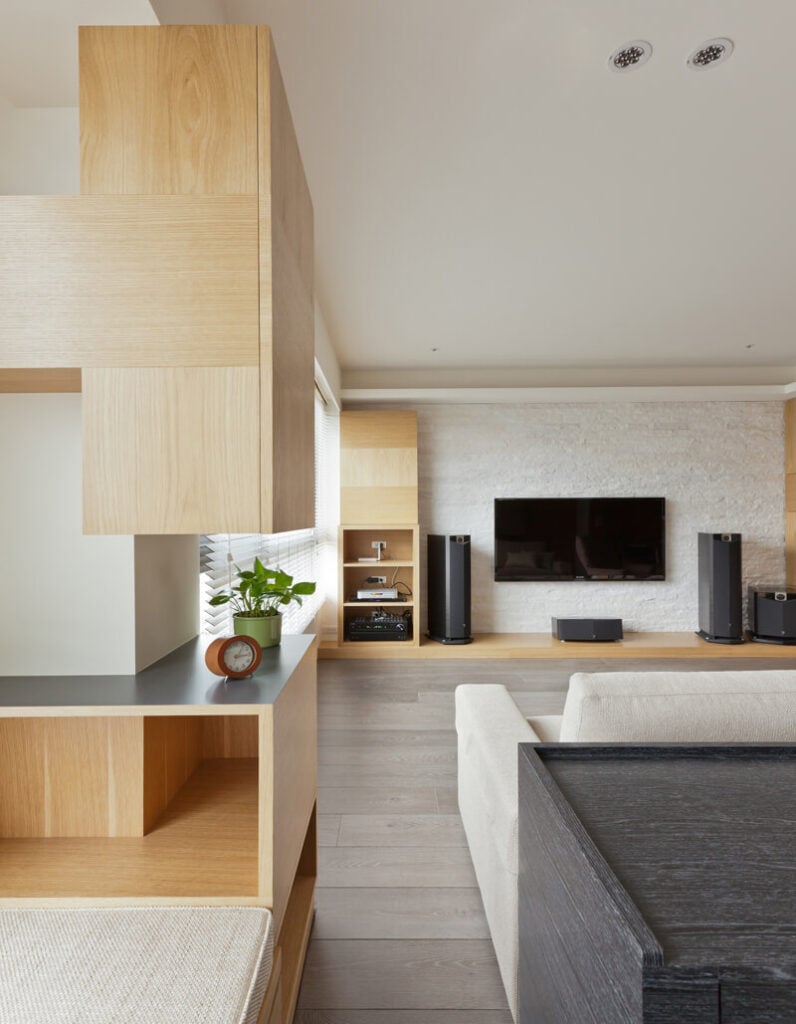 深色的办公桌与浅色的软垫、温暖的木材色调和白色的墙壁形成对比。