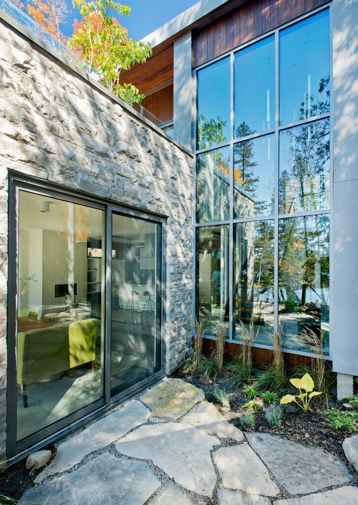 中央开放的两层空间从地面到屋顶都有窗户。左边舒适的客厅空间由石头包裹，与主屋结构的木材形成对比。