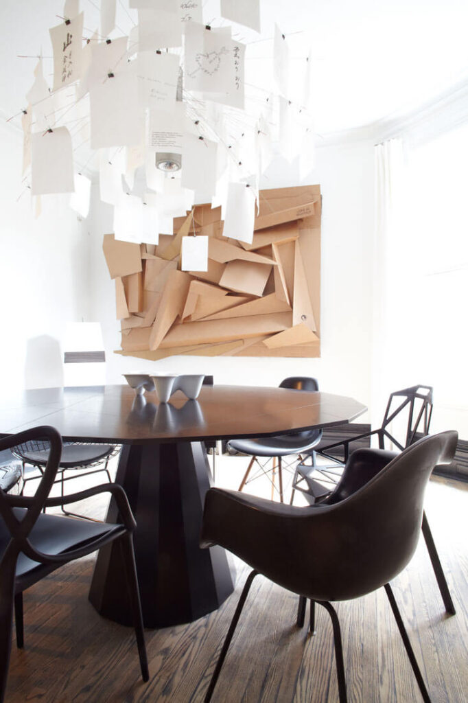 餐厅里有一套引人注目的装饰:吊灯和挂在墙上的大型纸雕塑增添了超现代的触感和强烈的视觉吸引力。黑色的餐桌周围环绕着各种风格的椅子。