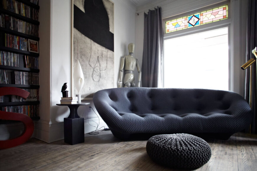 这款沙发体现了整个家庭弯曲的当代家具，与庄严的白墙和柔和的硬木地板形成对比。大型艺术作品随处可见。