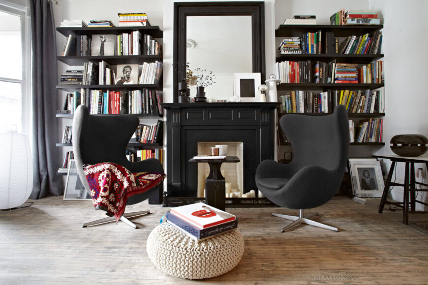 这个舒适的客厅设置完美地说明了整个家的传统和现代元素的折衷混合。硬木地板与黑白空间相遇，中间有一座黑色壁炉，两侧有一对蛋形扶手椅。