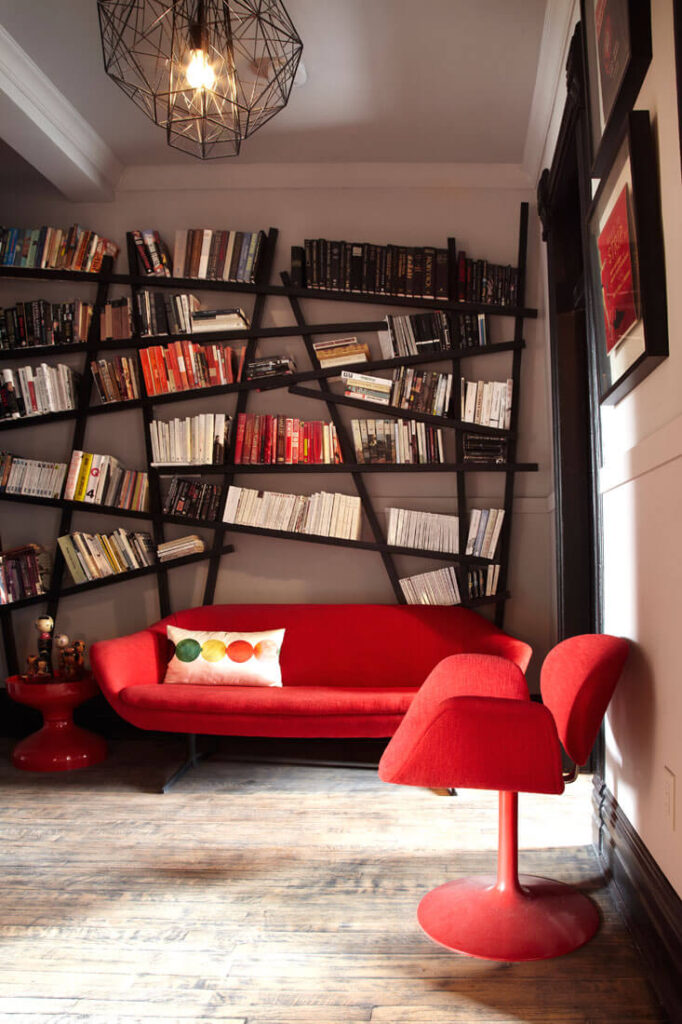 这个房间以独特的“随意”现代主义书架为特色，有棱角的黑色线条与照明框架相呼应。鲜红色的家具与宁静的环境形成对比。