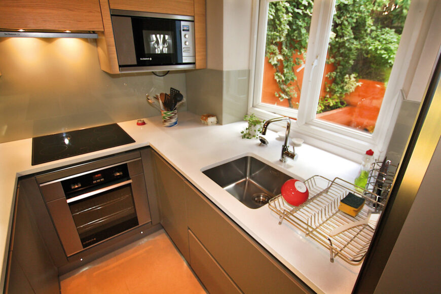 这个舒适的厨房中的白色u型台面有助于实现明亮和开放的外观，特别是与橱柜和后挡板形成对比。