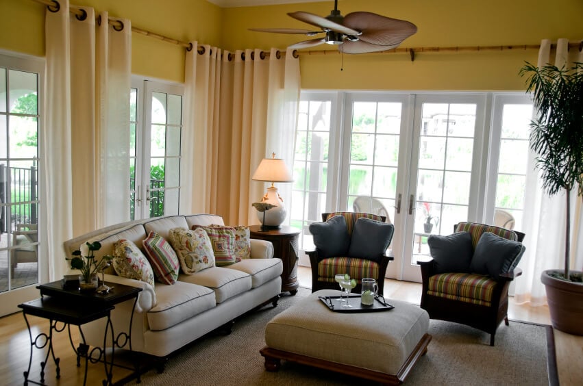 这间休闲的客厅和阳光房有竹窗帘杆，延伸到房间周围。带套环的透明窗帘可以很容易地在房间里移动。