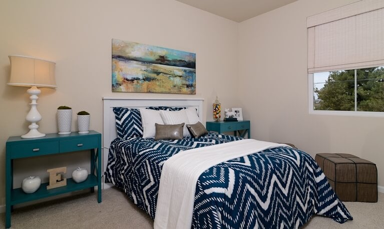 主卧室的特点是醒目的蓝色和白色的混合，在床的两侧有一对大胆的边桌。一幅巨大的油画悬挂在上面，而立方体的凳子放在窗户下面。