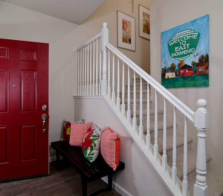 门厅里有白色漆的楼梯和丰富的深色木凳，从红色的前门到枕头和绘画，到处都是大胆的颜色。