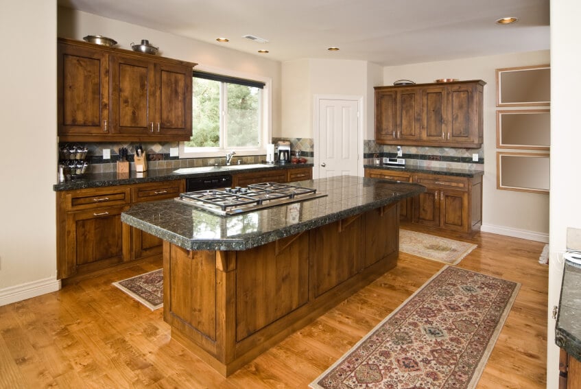 这些深色橱柜的华丽天然木材与浅色木地板的纹理相得益彰，给人一种质朴、农舍的感觉，而不会偏离这个优雅的厨房。