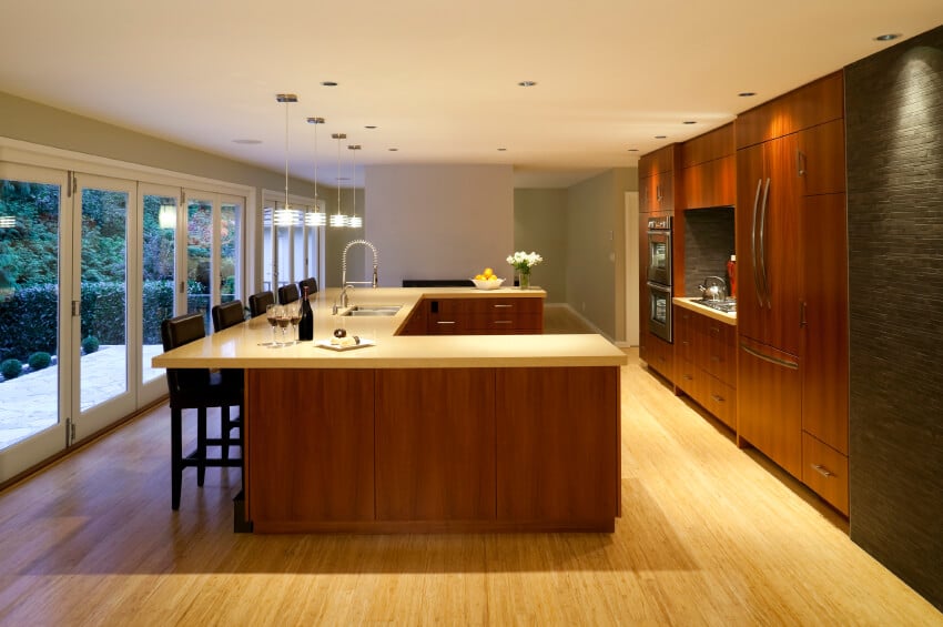 这间整洁的厨房因浅色木地板和配套的台面而显得更加明亮。天花板上的凹进式射灯突出了橱柜温暖的青铜色调。有纹理的石头强调墙完成了外观。