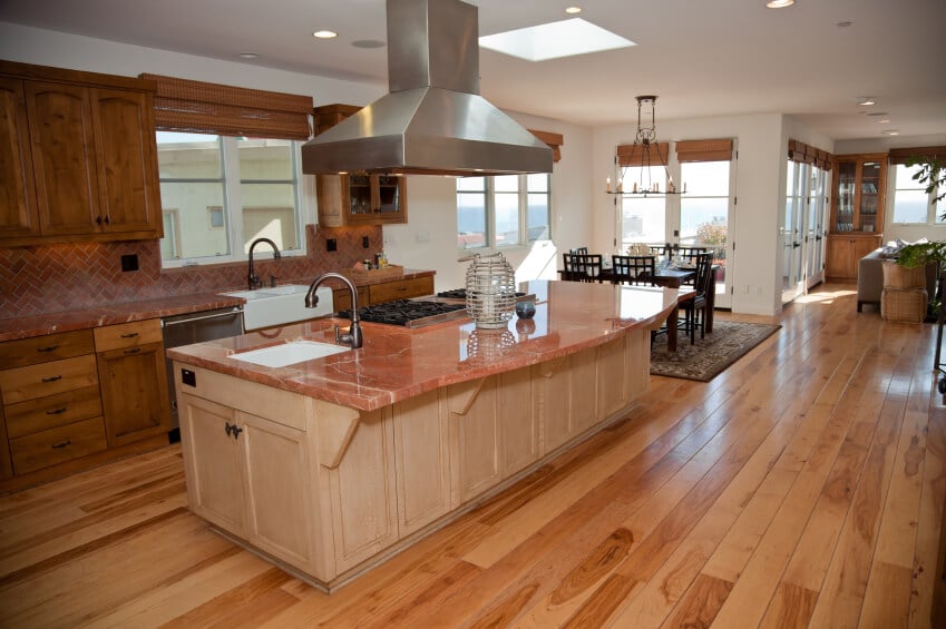 这个奢华的厨房有迷人的粉红色花岗岩柜台和砖一样的后挡板。橱柜的暖色木材衬托出浅色木地板的深色色调。