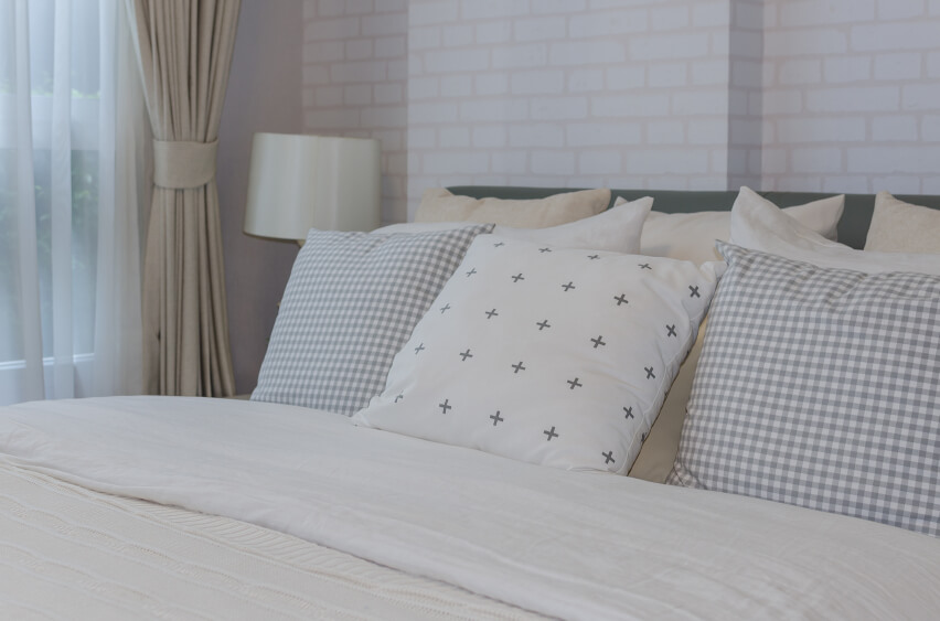 简单的方形抱枕在白色砖墙和象牙色床单的映衬下很有冲击力。