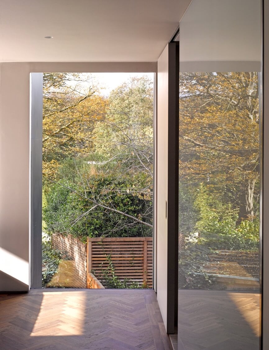 透过全高的玻璃向下看，周围的绿色植物将住宅包裹在一个私人空间中，而玻璃有助于消除室内和室外的界限。