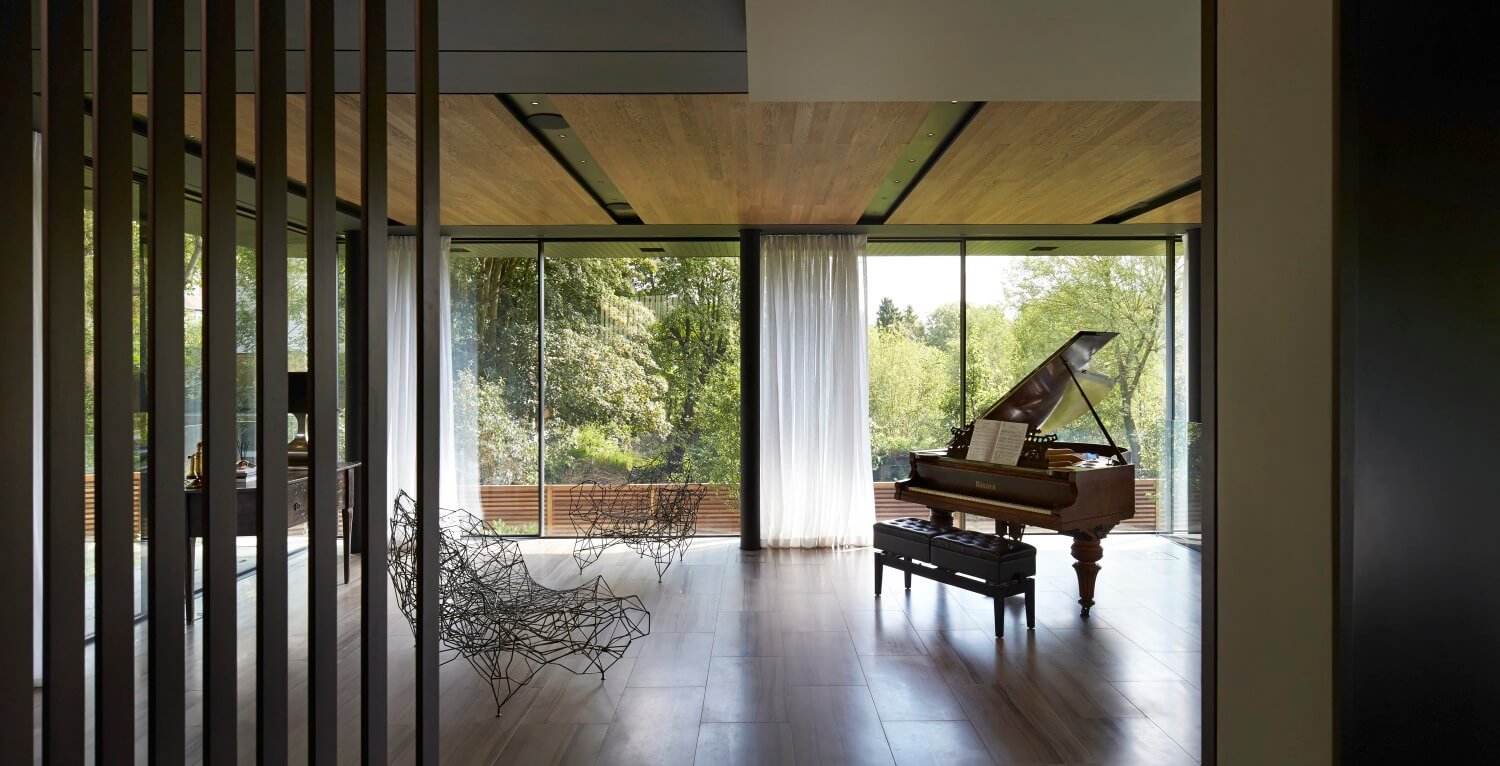 这个极简主义的空间除了古典钢琴外，还有一对前卫的线框椅子和传统的小木桌。