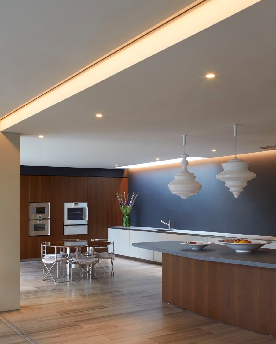 低层的开放式空间包括这个禅宗风格的厨房，混合了丰富的木材色调和时尚的现代风格。右边的大岛台补充了冗长的极简主义台面。