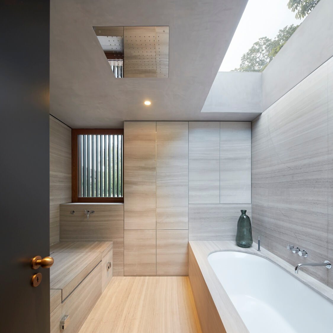 浴室从地面到地面都被丰富的大理石浸透，通过天窗在自然光下发光。该设计包括一个雨淋头在中心，为一个完全开放的淋浴设计。