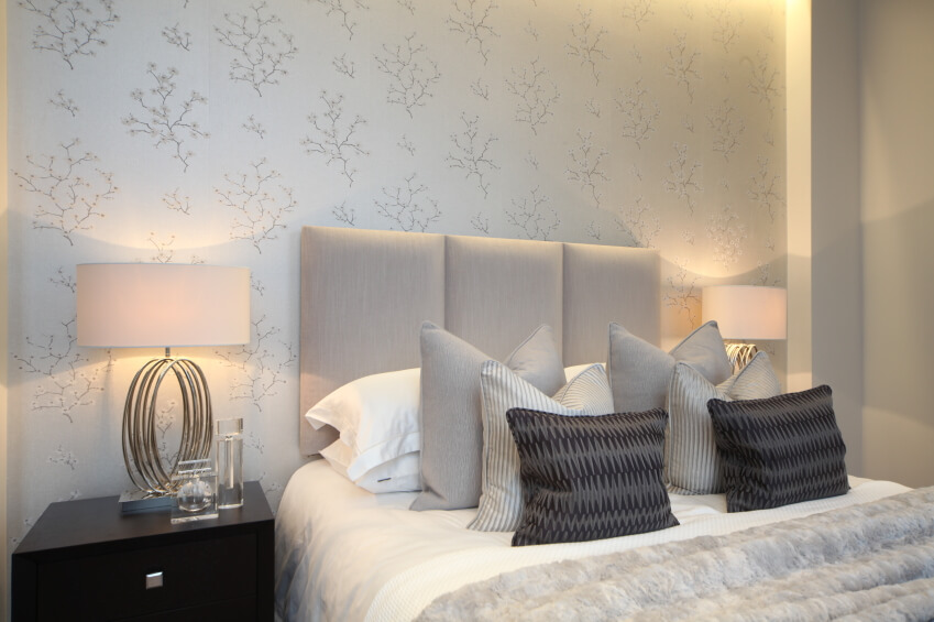 这个非凡的卧室以精致的奶油色和米色图案的壁纸为特色，将中性的房间与安静的决心联系在一起。现代金属灯优雅的乌木茶几，而一个美妙的安排扔和强调枕头坐在床上。