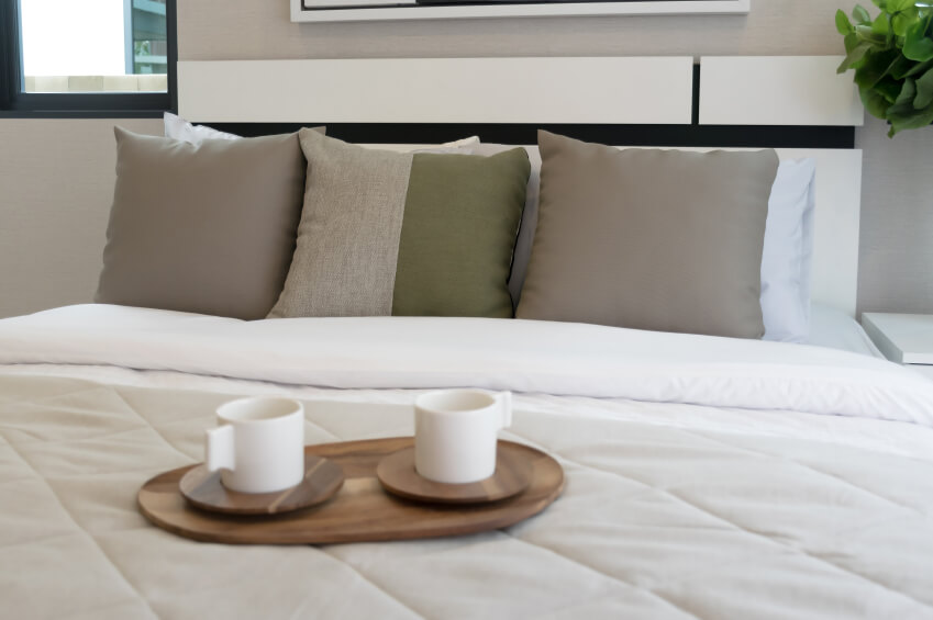 中性空间采用对称。棕色抱枕位于两种色调的重点枕头旁边，而整个地块由传统的白色枕头支撑。
