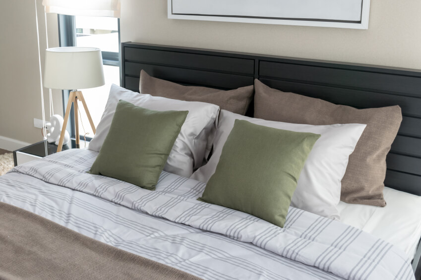精心安排的枕头为这种对称排列的条纹床单增添了光彩。这个安静的男性空间吸引了人们的注意力，但又不让人感到压抑，而一个简单的床头板则监督着床，与房间的中性形成了强烈的对比。