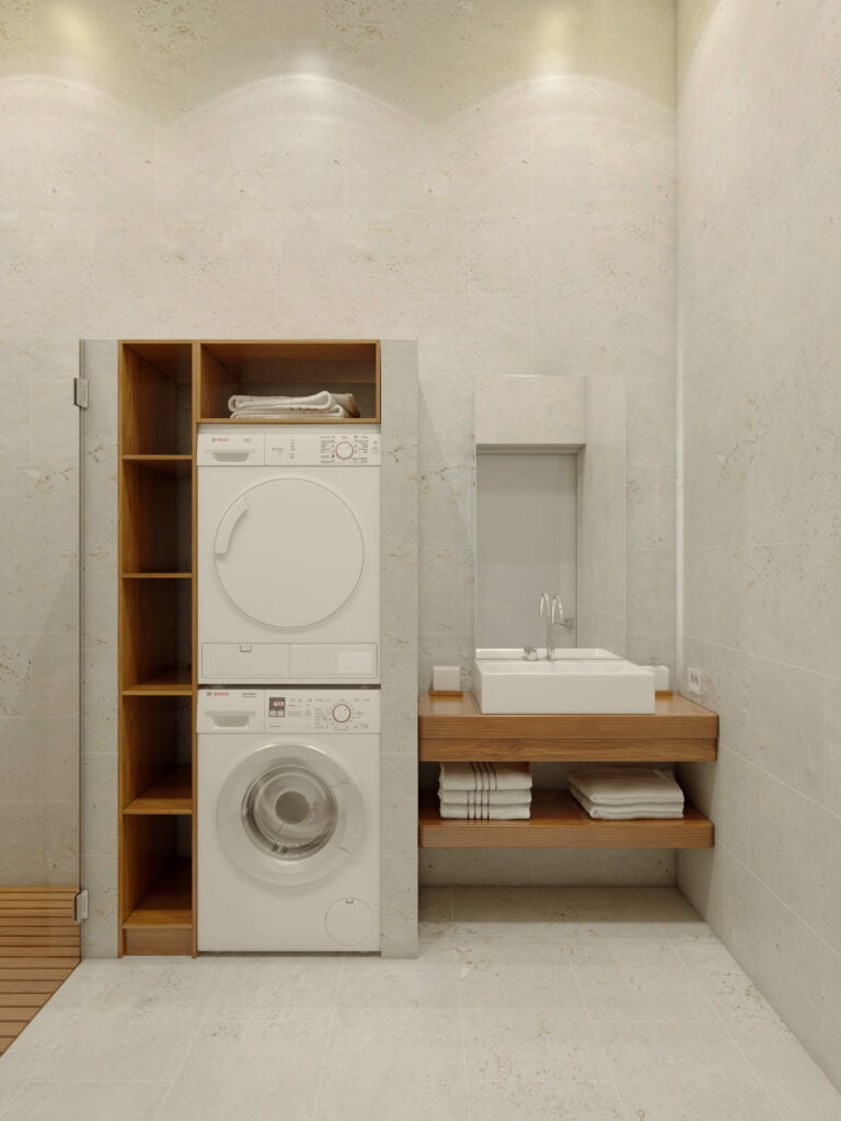 洗衣机安装在一个空间内，两侧是储物柜和另一个浮动梳妆台，毛巾存储在大型方形容器水槽下方。