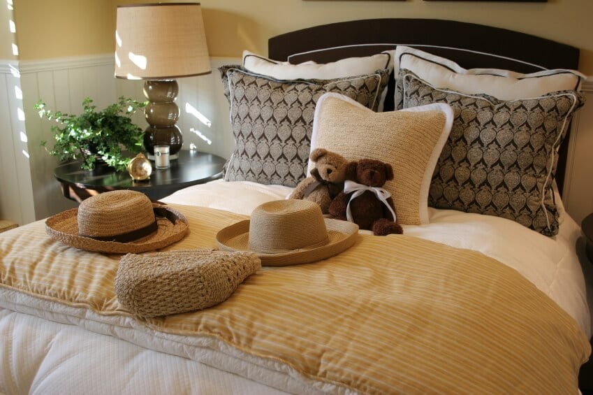 这间迷人的卧室展示了各种颜色、图案和纹理。天然纤维的方形强调枕头可以支撑两只可爱的泰迪熊，与各种稻草装饰口音完美搭配。后面深色的长方形抱枕与浅色的枕头形成了鲜明的对比，而深色的床头板则提供了额外的丰富和美丽。