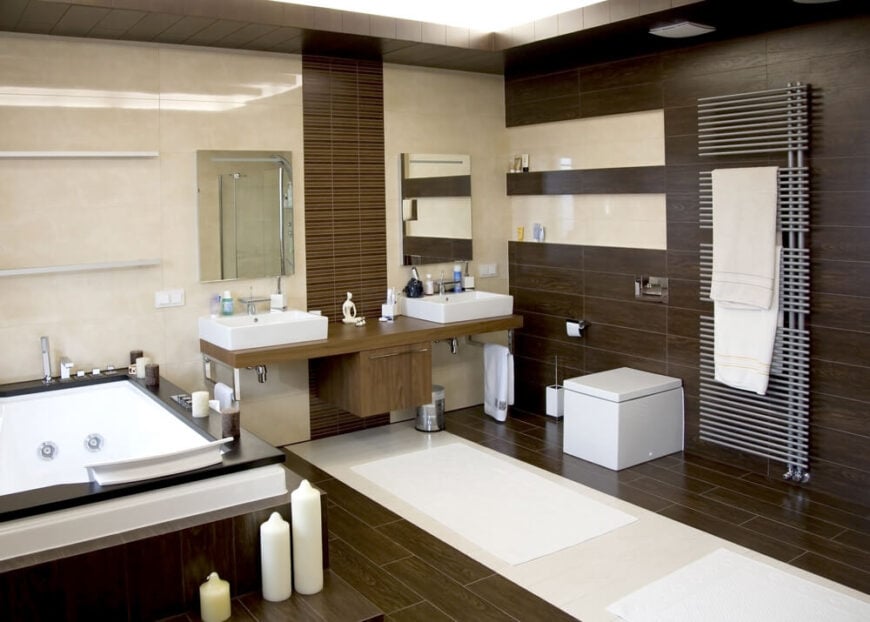 这个禅意式的浴室突出了对纹理和平衡的关注，深色木地板和右墙，搭配米色大理石墙。浮动的木制双梳妆台上有一对容器水槽，而左侧则是一个深色木材框架的大型浴缸。