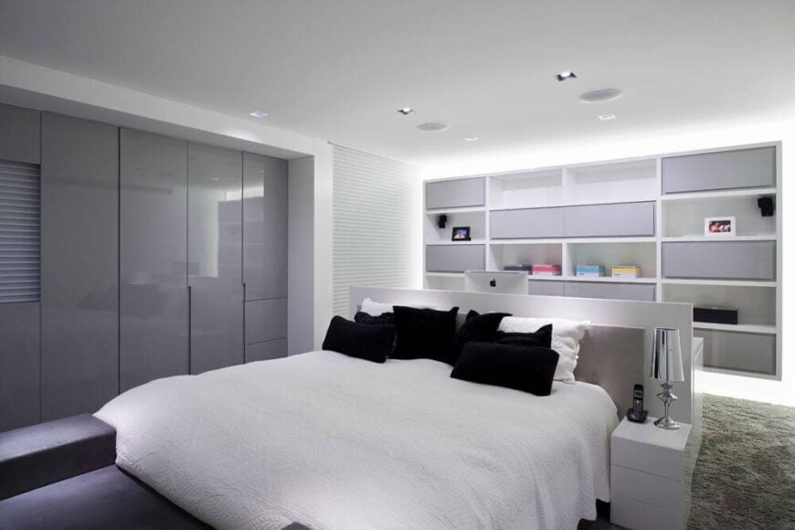 主卧室也是原始的白色，布局独特。床不是靠墙放的，而是放在房间中央，靠着一张稍高的桌子。这样的布置在视觉上将卧室的两个部分分开:睡眠区和工作区。