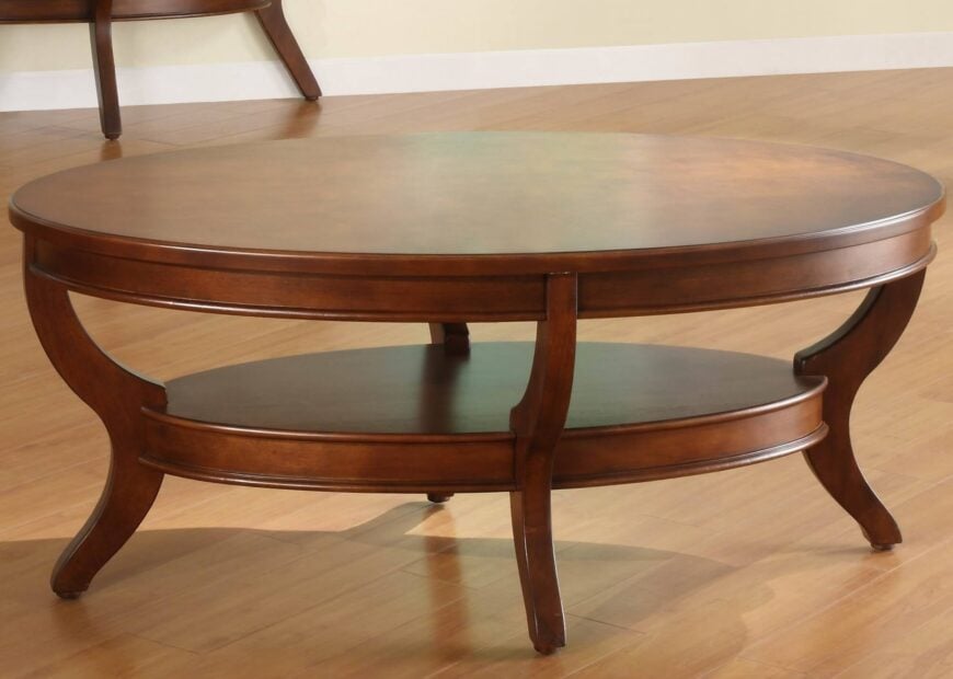 这款复杂雕刻的椭圆形咖啡桌有两个厚板表面，在弯曲的桌腿之间夹着一个较小的下层存储空间。丰富，温暖色调的污渍帮助它混合几乎任何风格的房间。