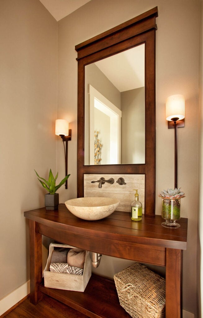 其中一间浴室以定制的深色木质梳妆台为特色，大理石容器水槽和后挡板位于框架内的高镜子下方。一个薄的，灯罩烛台旁边的作品。