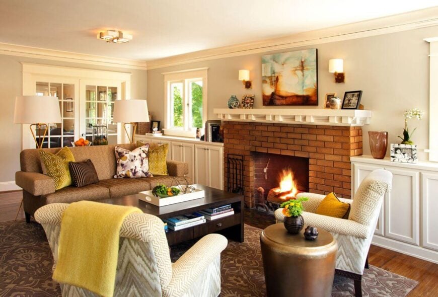 整个客厅的景色，有一个漂亮的红砖壁炉和有图案的地毯。深色的木头咖啡桌包括抽屉和桌面下面的架子。内置家具沿着壁炉的墙壁延伸，有充足的存储空间，也是展示照片和其他装饰品的绝佳场所。