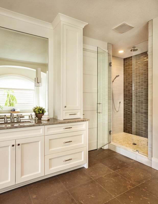 两间主浴室中的一间配有定制橱柜和一间贴着米色和棕色瓷砖的步入式淋浴间。