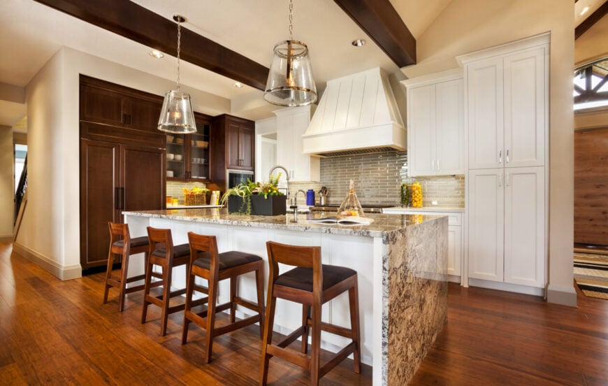 整个厨房的视野，展示了对比鲜明的白色和深色木橱柜和巨大的花岗岩岛台。