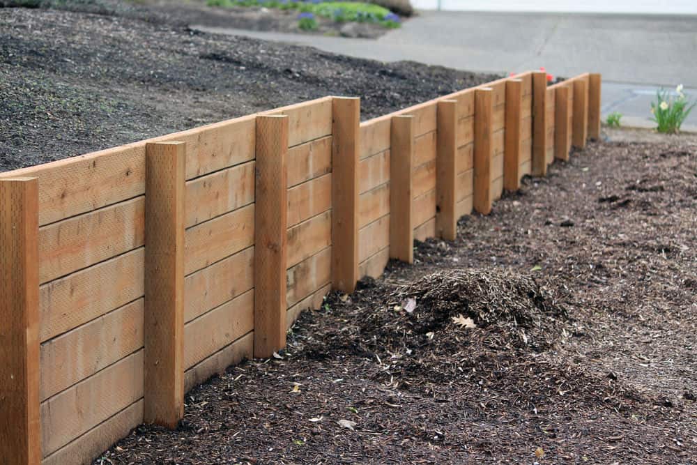 一块膨胀的土质地面上有一堵镶着木板的挡土墙，当你走近时，它的高度会更高。