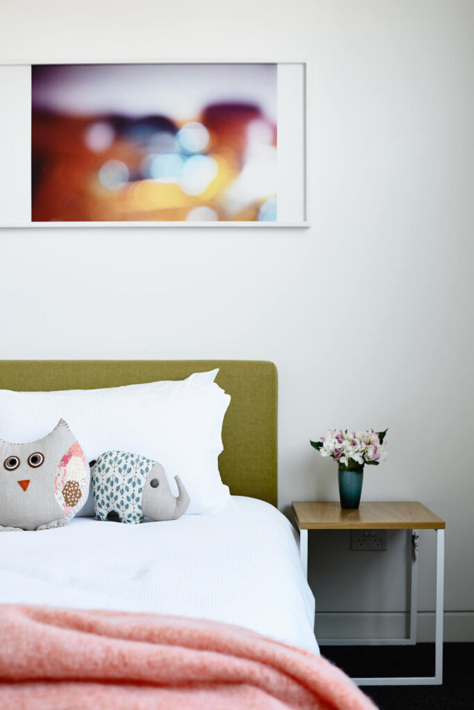 这个精致甜美的女孩房间以简单的家具和轻快的调色板为特色，包括淡粉色和浅绿色。猫头鹰和大象毛绒装饰着床。