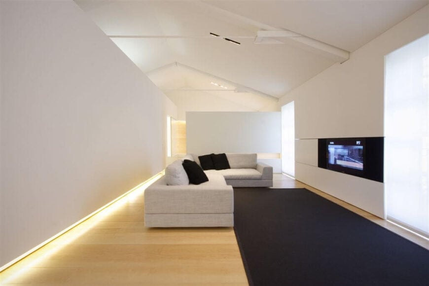 这个极简主义的客厅不需要很多东西，它是优雅和独特的。硬木地板在墙壁下隐藏的发光灯旁闪烁着明亮的光芒。