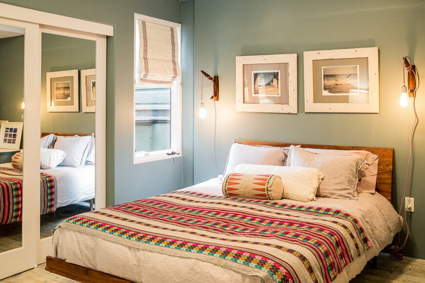 这个房间还包括一个带镜子的衣橱，但最大的特色可能是色彩鲜艳的床上用品。床的两侧是工业壁式壁灯。