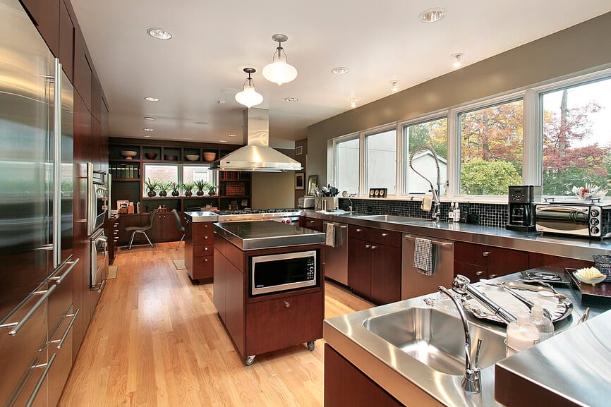 这间现代风格的厨房在厨房台面上设有观景窗。美丽的光线通过窗户进入，为这个金属和硬木设计创造了美妙的光芒。