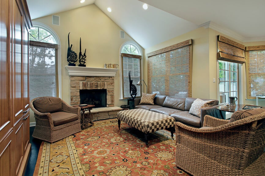 这个折衷的客厅设有一个小石头壁炉，柳条椅子搭配皮革沙发，和棋盘图案的脚垫。天然纤维窗帘可以覆盖在众多的窗户上。